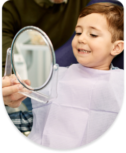 Mały chłopiec z zadowoleniem oglądający efekty leczenia ortodontycznego w lusterku