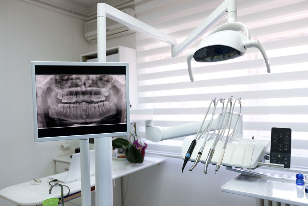 Nowoczesny gabinet stomatologiczny widoczna lampa zabiegowa konsola z urządzeniami na monitorze zdjęcie pantomograficzne zębów 1