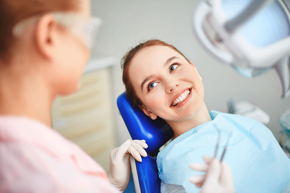 Lekarz ortodonta i uśmiechnięta dziewczyna siedzi na fotelu stomatologicznym 1
